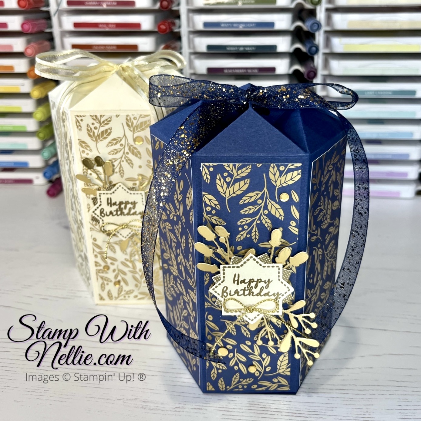 Photo of a dark blue and gold hexagonal gift box in the foreground with a cream and gold one behind it