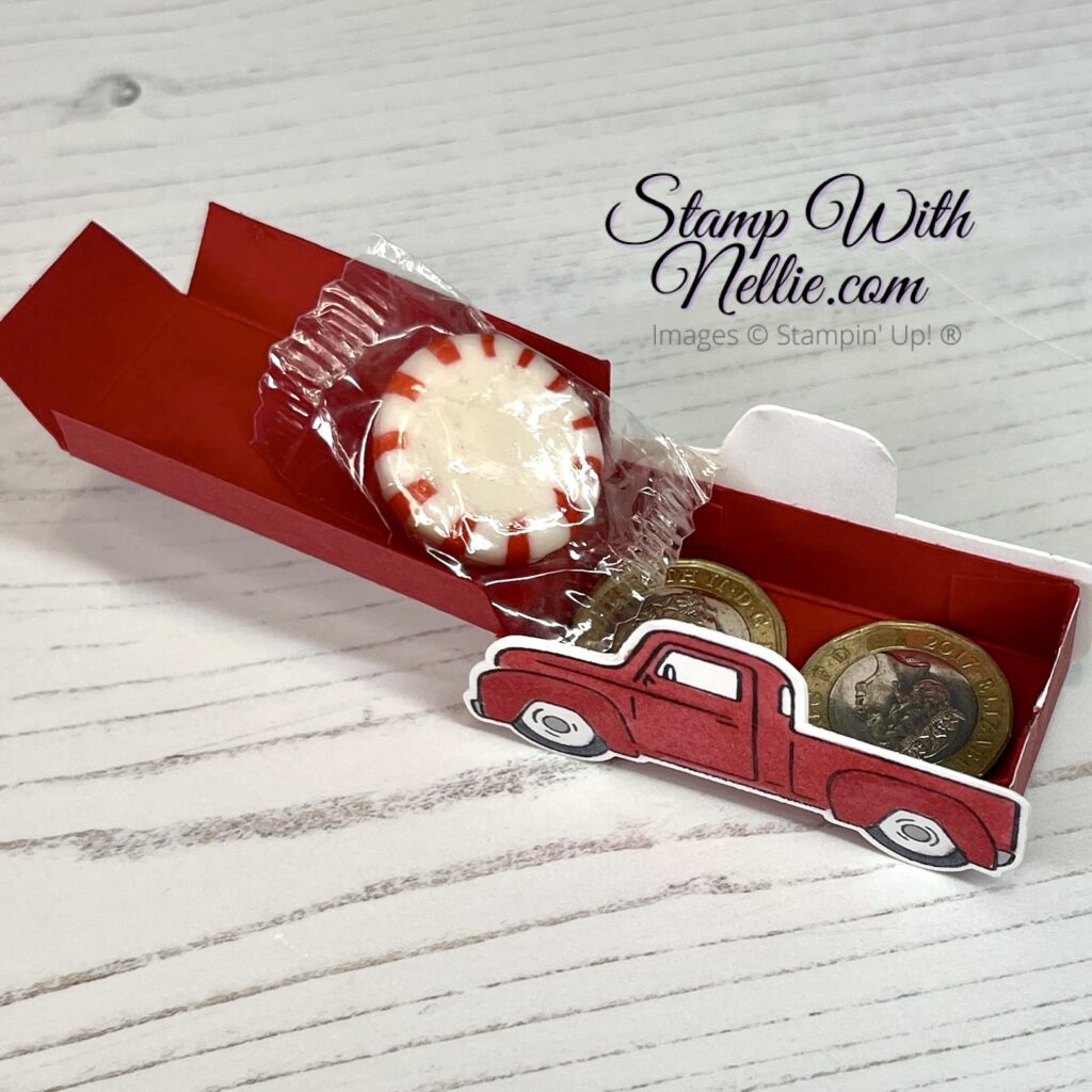 Photo of a little red truck treat box with its lid open. There's a sweetie and two pound coins inside.
