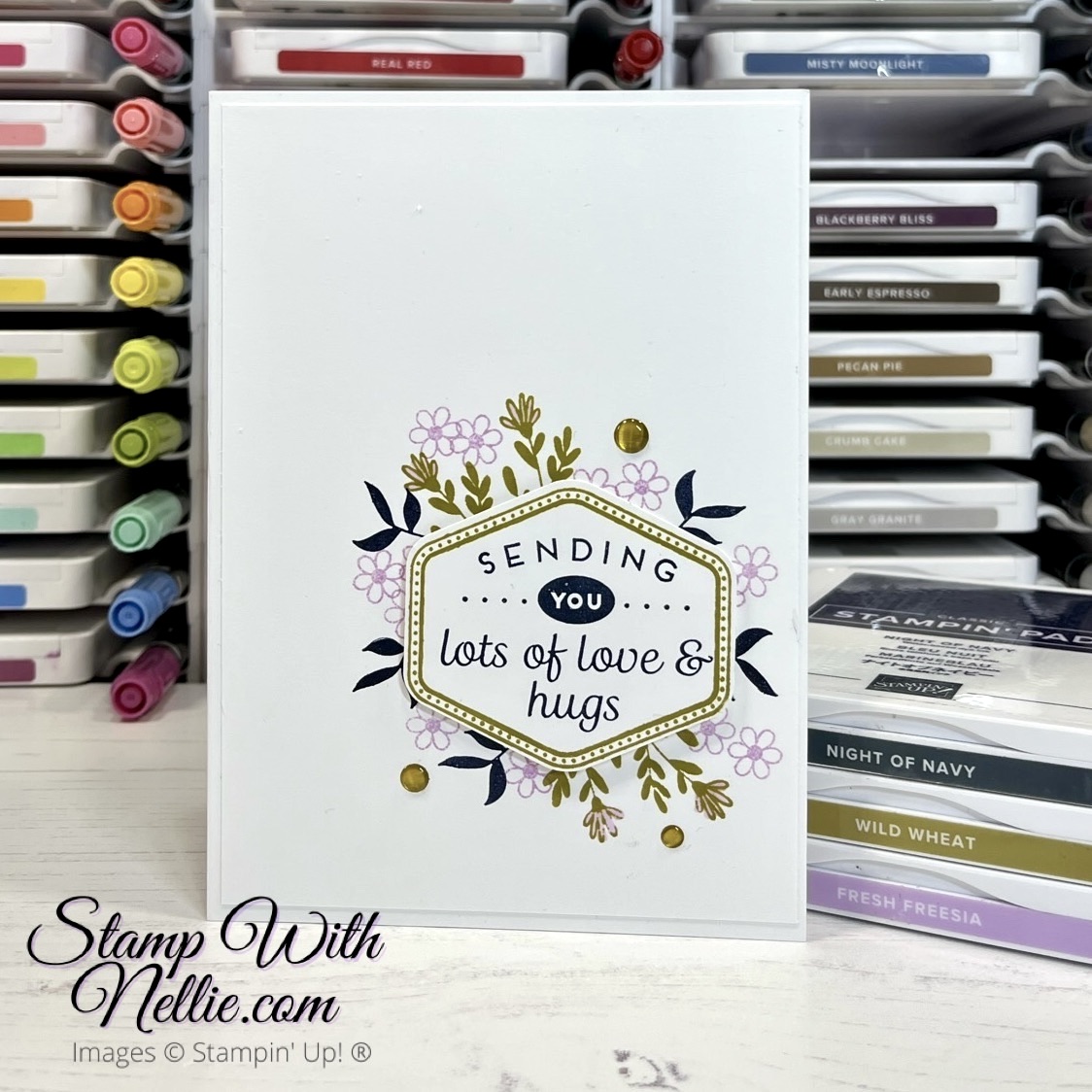 White card with some small flowers and leaves stamped in the 3 colours of this challenge.  There's a hexagon shaped label over some of the stamping.  The sentiment reads Sending You Lots of Love & Hugs